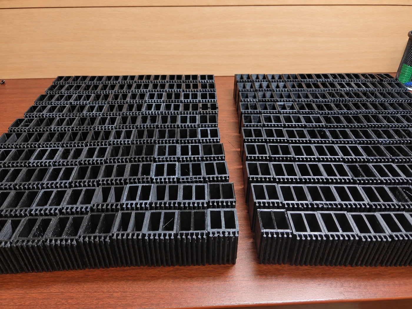 Več enakih črnih 3D natisnjenih komponent, urejenih po vrstah